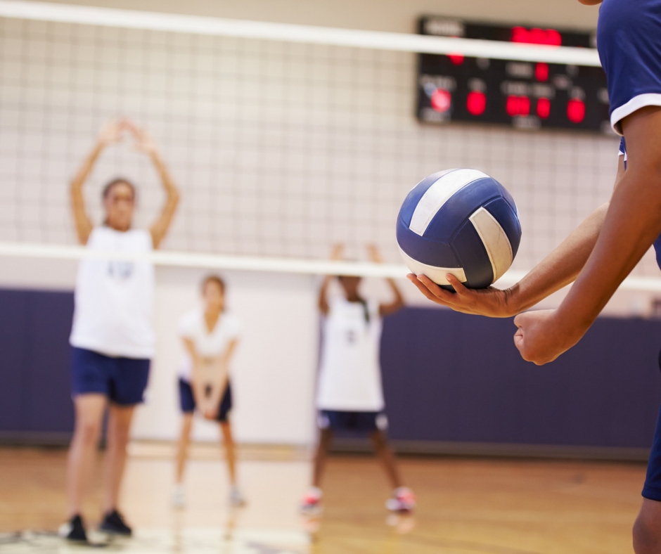 Girls playing volleyball inside a gymnasium