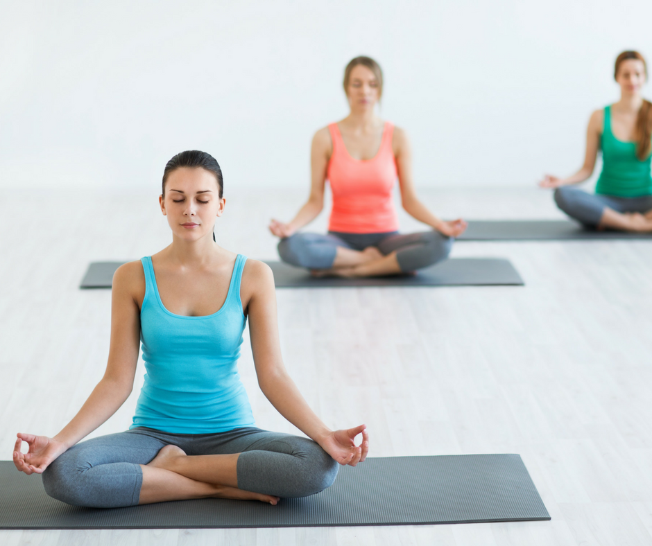 3 woman sitting cross legged practicing yoga