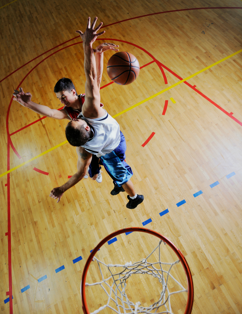 two male teenagers playing one on one basketball