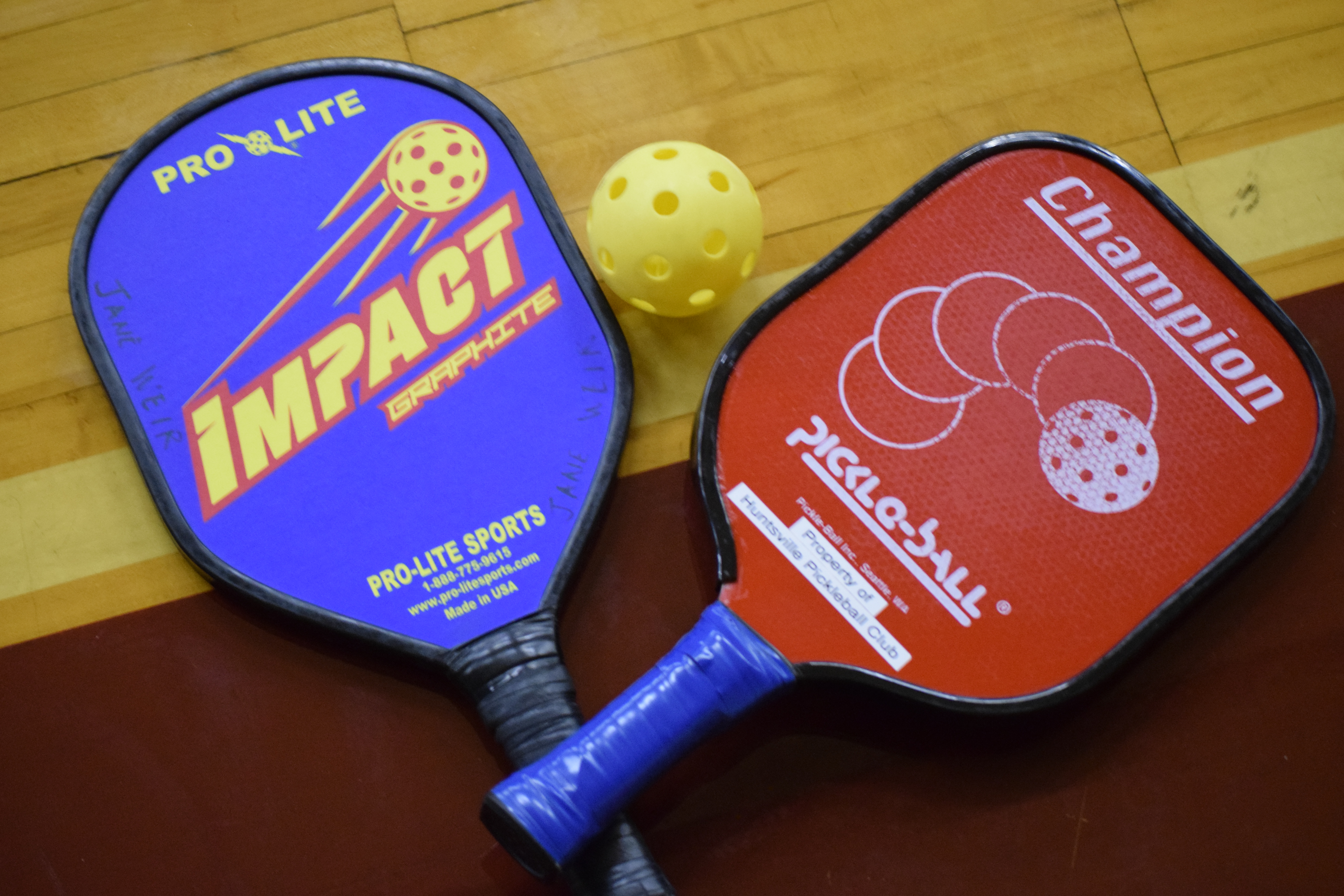 Two pickleball paddles and a ball