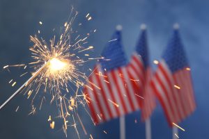 Burning sparkler against USA flags, closeup with space for text. Happy Independence Day