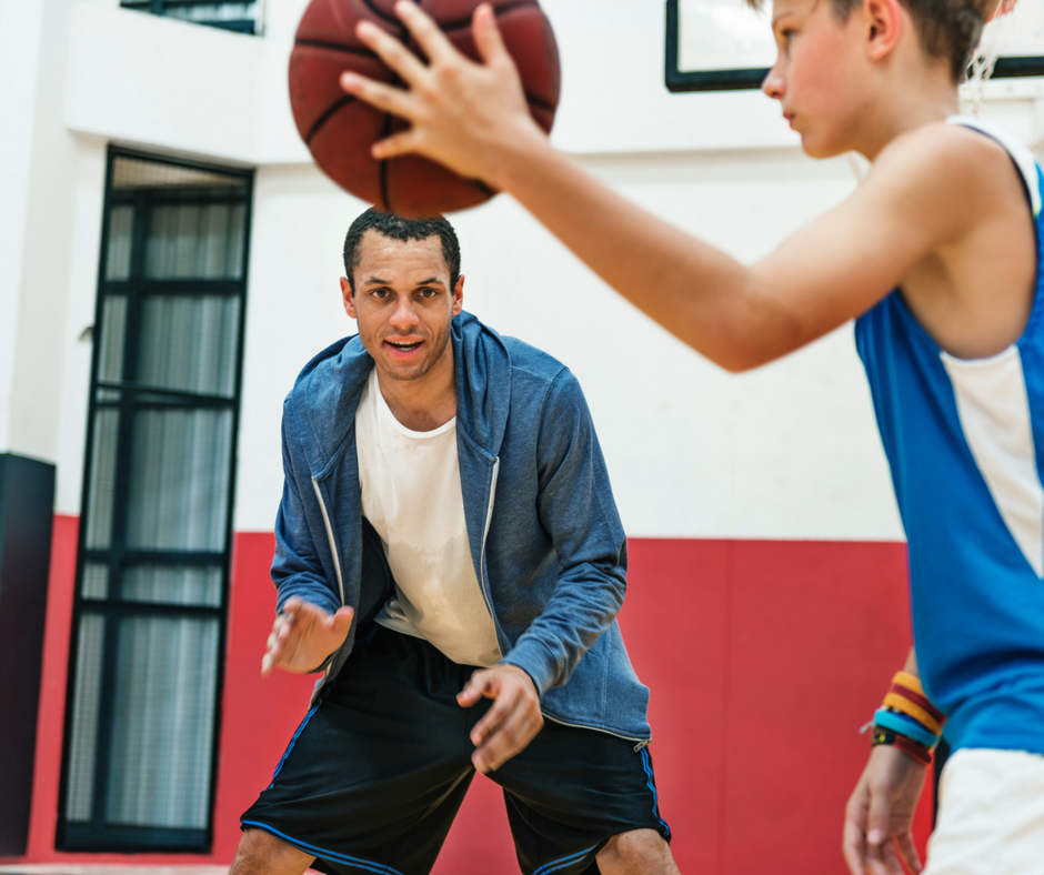 child and coach playing basketball