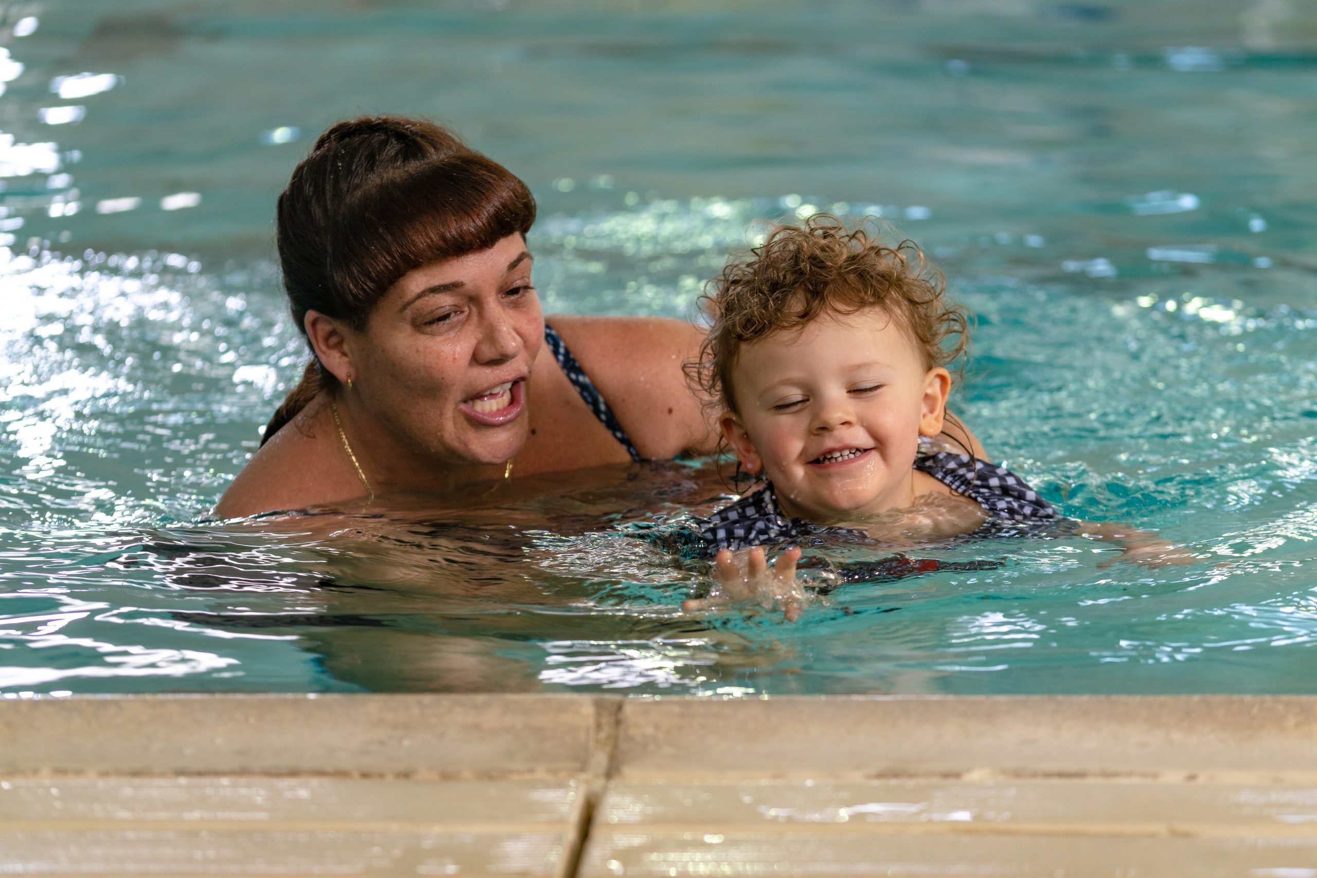 Female instructor with female toddler being pulled through the water.