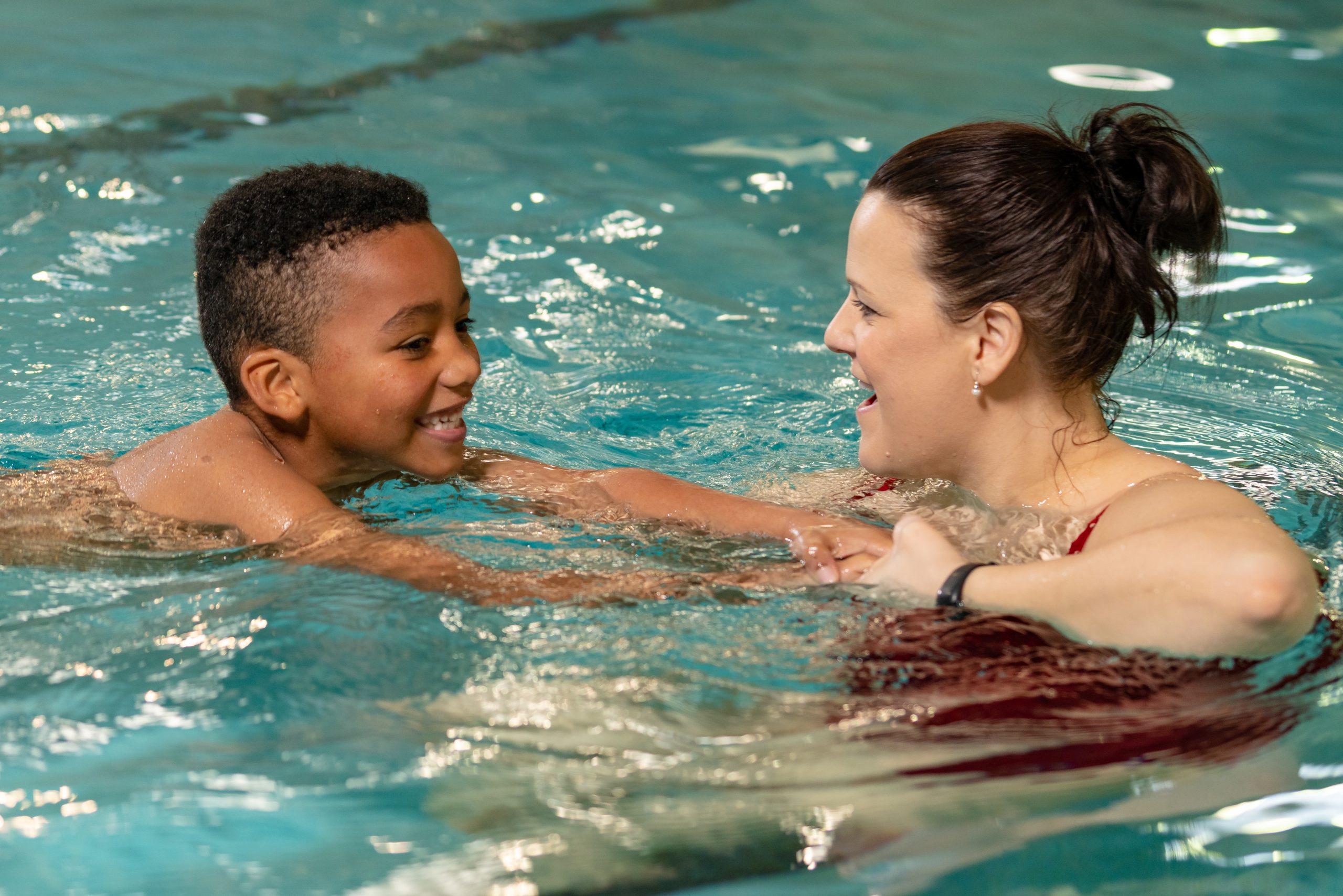 Female instructor pulling small boy through the water.