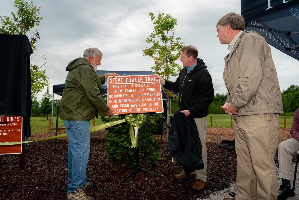 Landscape Management Supervisor Steve Fowler looks at a sign naming a trail in his honor