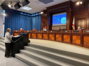 Finance director Penny Smith at a podium speaking about the Covid-19 budget impacts to the mayor and city council
