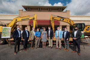 Picture of developer, mayor, Council member in front of the old Haysland Square stores with backhoes ready to begin construction