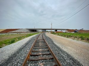 Railroad tracks leading underneath an elevated bridge on Old Highway 20