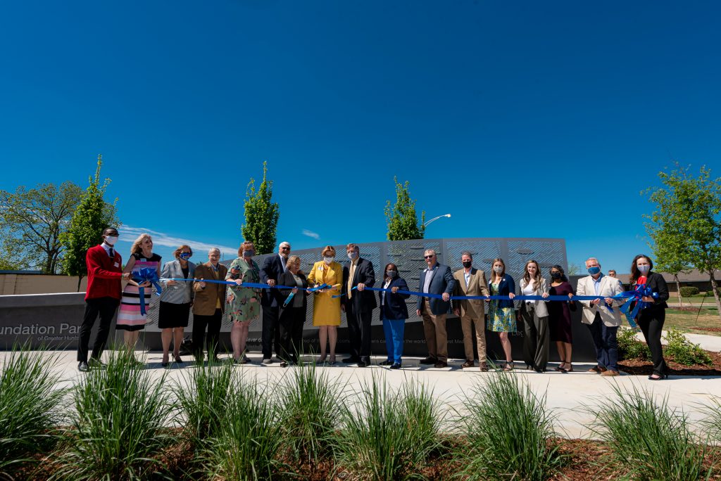 People cutting a ribbon in front of a wall outdoors.