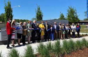Mayor Battle, donors, and city leaders gather in front of a donor wall at the new Community Foundation park to cut a large blue ribbon and officially open the park