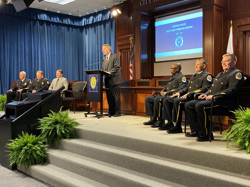 Mayor Tommy Battle at the podium with Police Chief Mark McMurray addresses the crowd with the three new deputy chiefs in the city council chambers of City Hall.