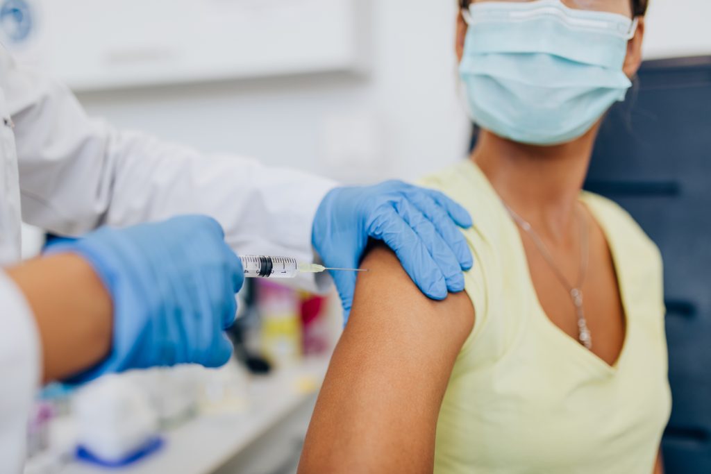 A young woman receives a vaccination in her right arm