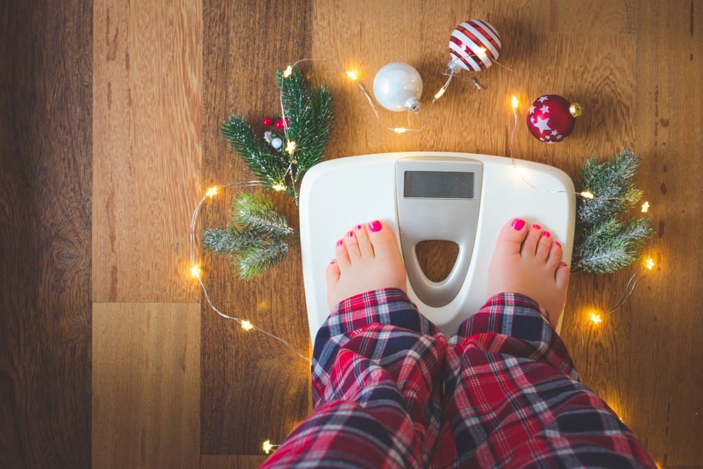 woman weighs on scale with holiday decor