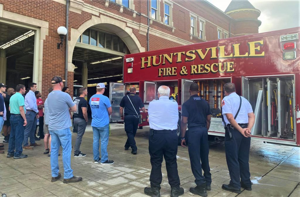 firefighters and recruit look at fire truck