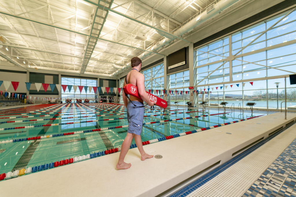 A young male lifeguard walks by the competition pool at the Huntsville Aquatics Center