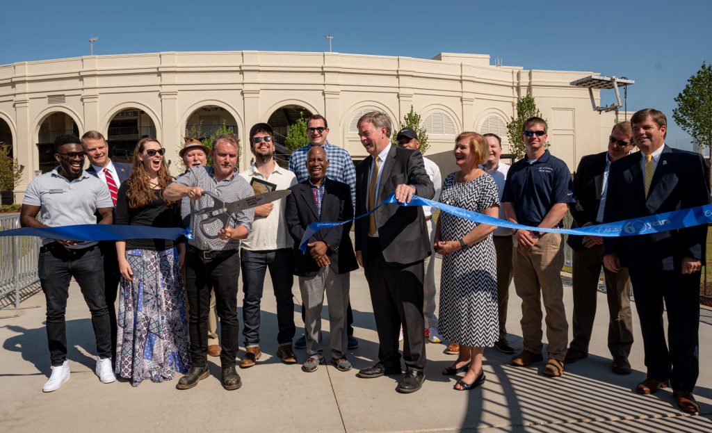 people cut a long blue ribbon in front of the new Orion amphitheater at MidCity in Huntsville