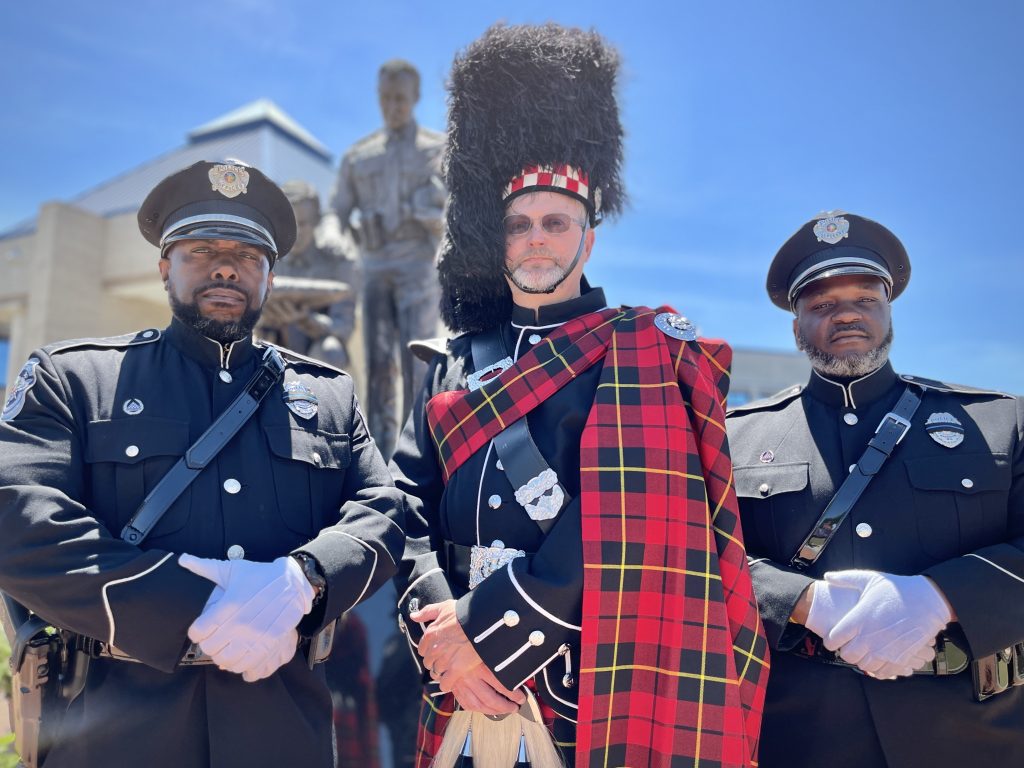 three police officers standing in front of the memorial in class A uniform