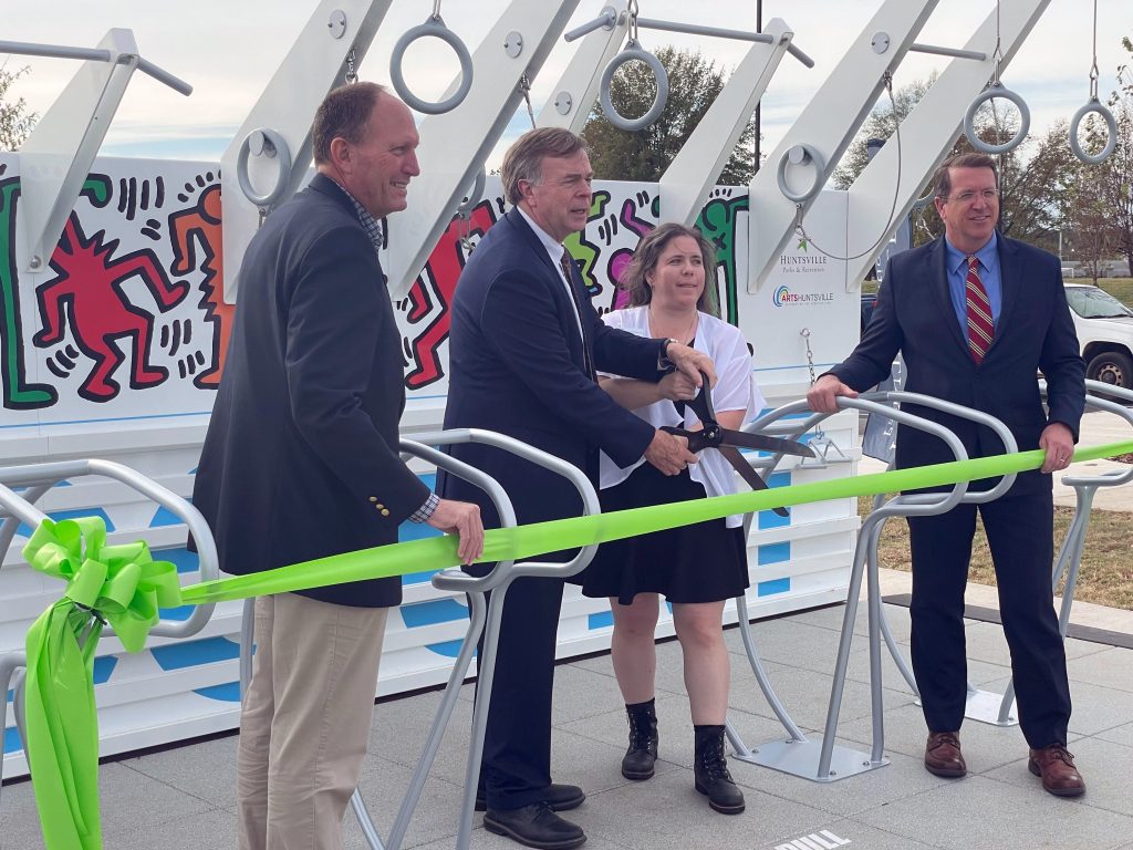 Men and women holding large scissors cutting a ribbon in the new fitness park