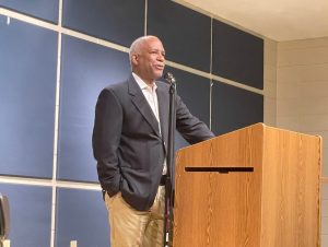 Man speaks in microphone behind podium