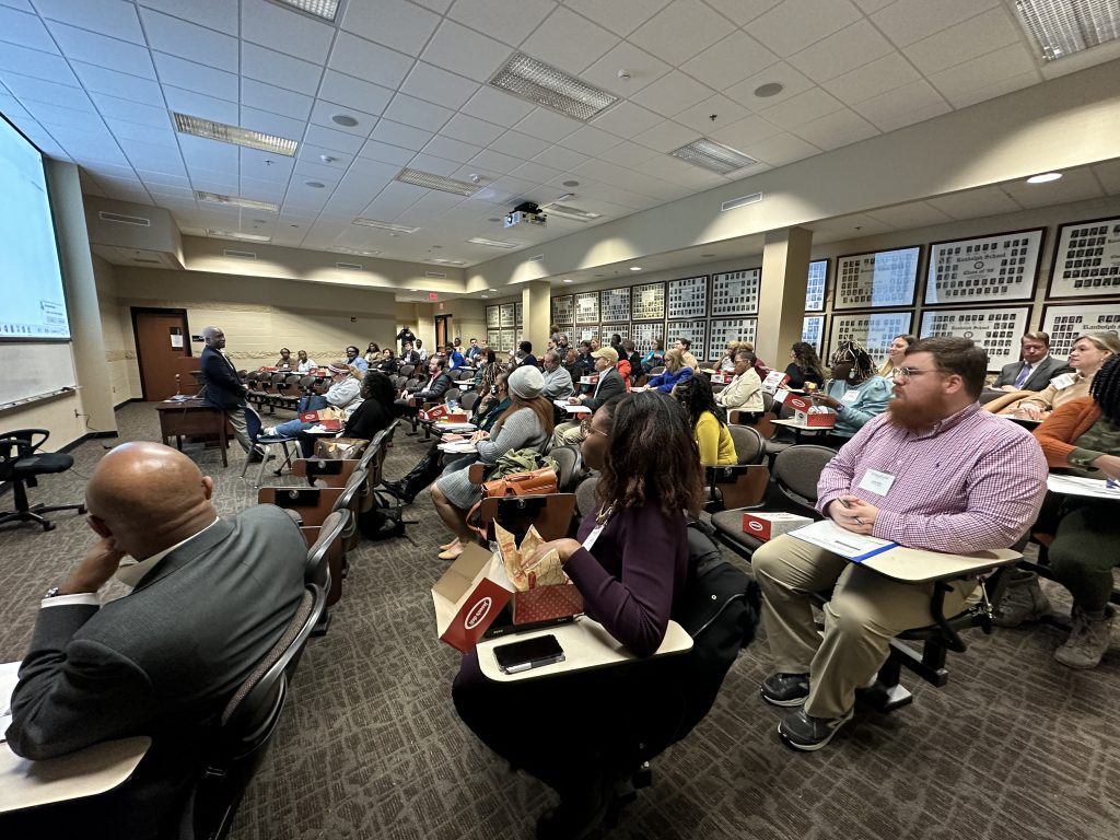 Group of adults in seats listen to speaker