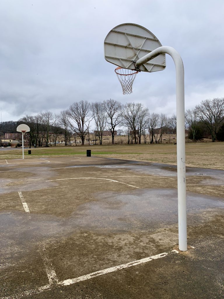 basketball goal and a worn court in need of renovation