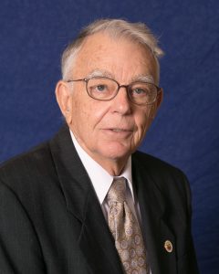 photo of a man with gray hair and glasses wearing a dark colored suit