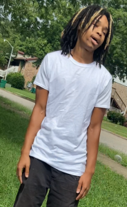 Man wanted for capital murder with long hair looking away from camera with white t-shirt and side profile view