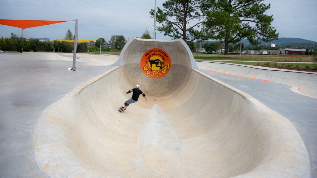 Man wearing helmet skateboards at new skatepark 