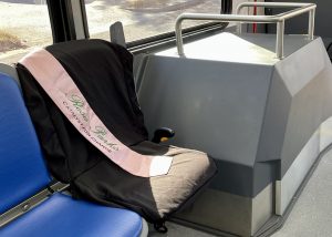 A bus seat is covered with a black cloth and pink sash honoring Rosa Parks.