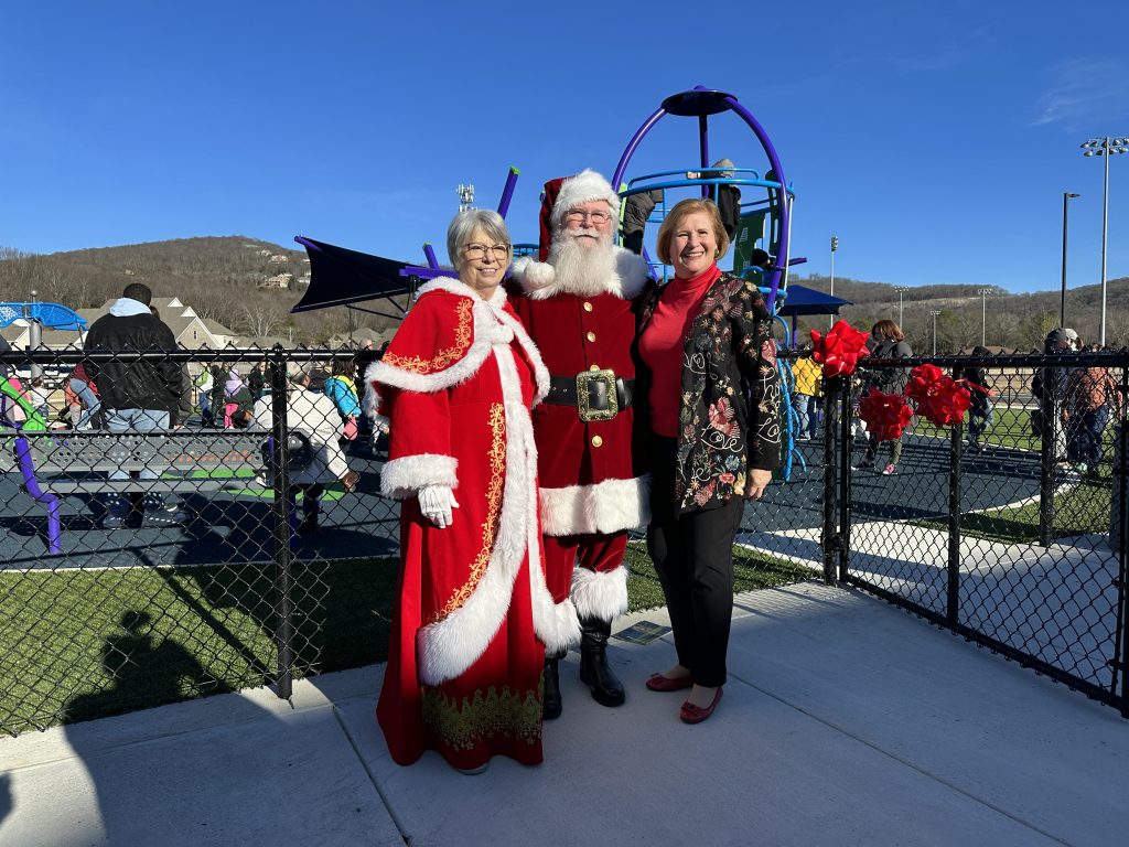 Santa and Mrs. Claus stand with Dr. Jennie Robinson in front of the new Sandra Moon playground
