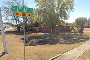 A street view of Lydia Drive, including the street sign. There is a house and sidewalk visible