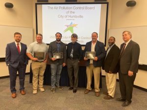 Air Pollution Control honorees display their awards at the Air Pollution Control Board Achievement Awards. There are seven men, some of which are dressed in suits. Mayor Tommy Battle is on the right.