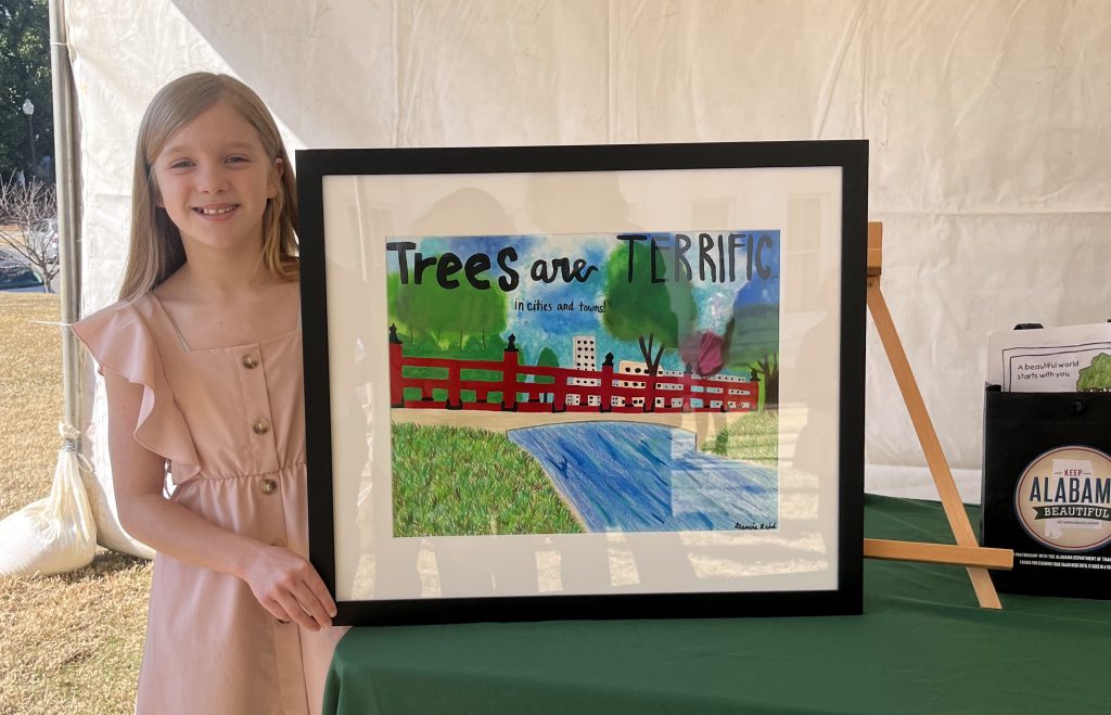 girl stands next to artwork she painted