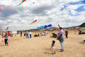 A man and his son fly a kite in John Hunt Park. There are other multicolored kites in the air.