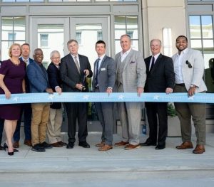 group of men and women standing behind ribbon to celebrate new building