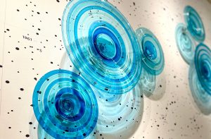 public art display of bluish circles on white wall