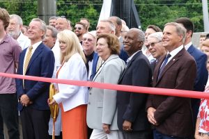 group of men and women preparing to cut a celebratory ribbon