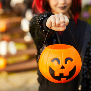 woman in black holding orange Halloween bucket