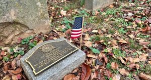 Photo of a headstone for Revolutionary War veteran John Ward and an American flag
