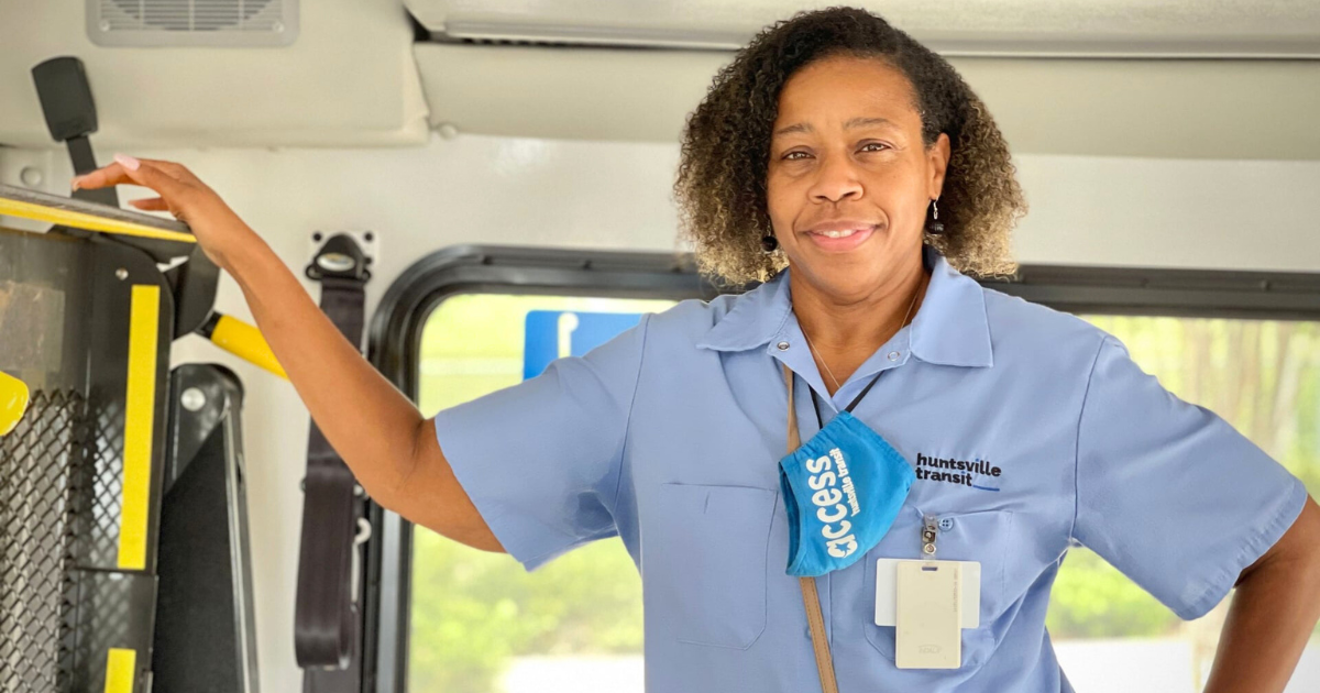 Photo of a female African American Access paratransit bus operator standing on a bus