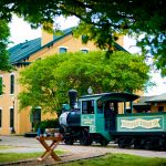 yellow depot building with a green train in front of it