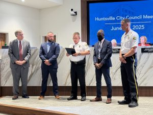 Mayor Battle, Huntsville Police Deputy Chiefs Hudson, Brooks and Johnson stand on stage in City Council Chambers to present Investigator Northcutt a life-saving medal.