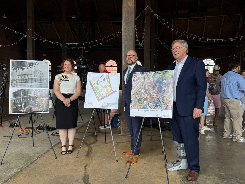 Mayor stands next to two people with poster boards showing maps of the depot property