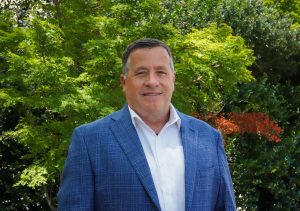 Man in a blue sport coat and white shirt standing outside