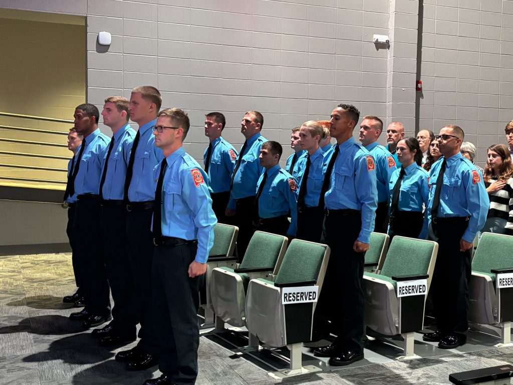 group of firefighters in light blue shirts and ties standing at attention