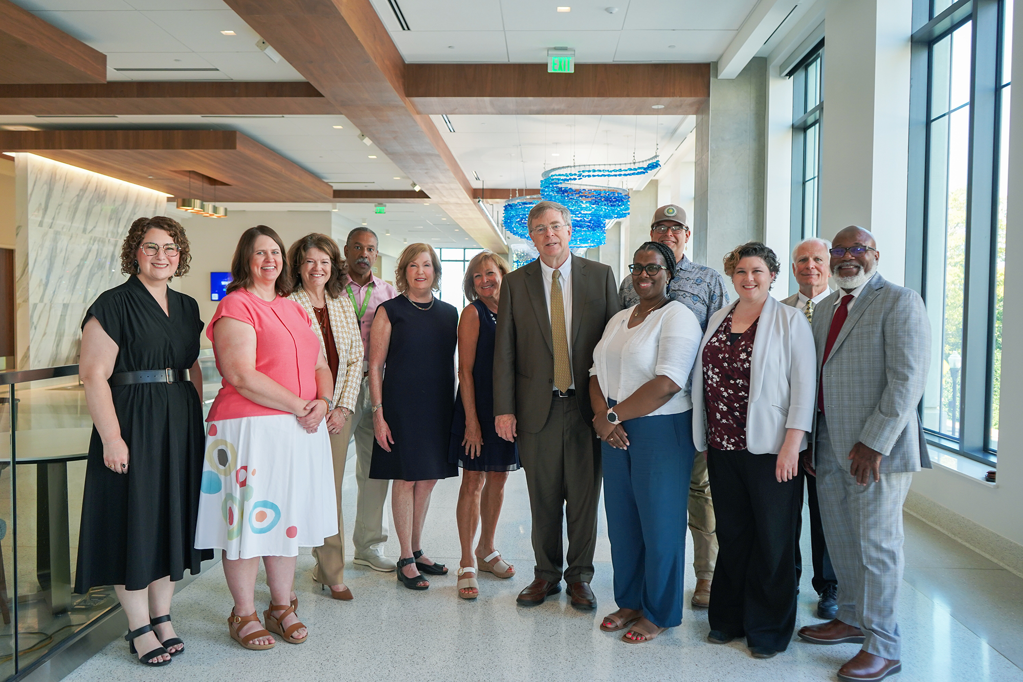 Diverse group of people making up the Huntsville Salutes America's 250th Committee standing with Mayor Tommy Battle in the lobby of Huntsville City Hall