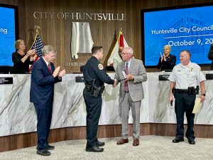 HPD Chief Kirk Giles, alongside Mayor Tommy Battle and HPD Captain Scott Widner, present the department's Life Saving Medal to Officer Colligan during Oct. 9 City Council meeting.
