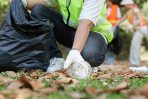 A person picks up a plastic bottle and other trash during local clean up day