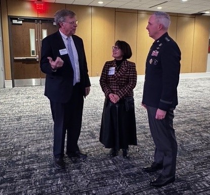 two men and woman have conversation in large meeting room