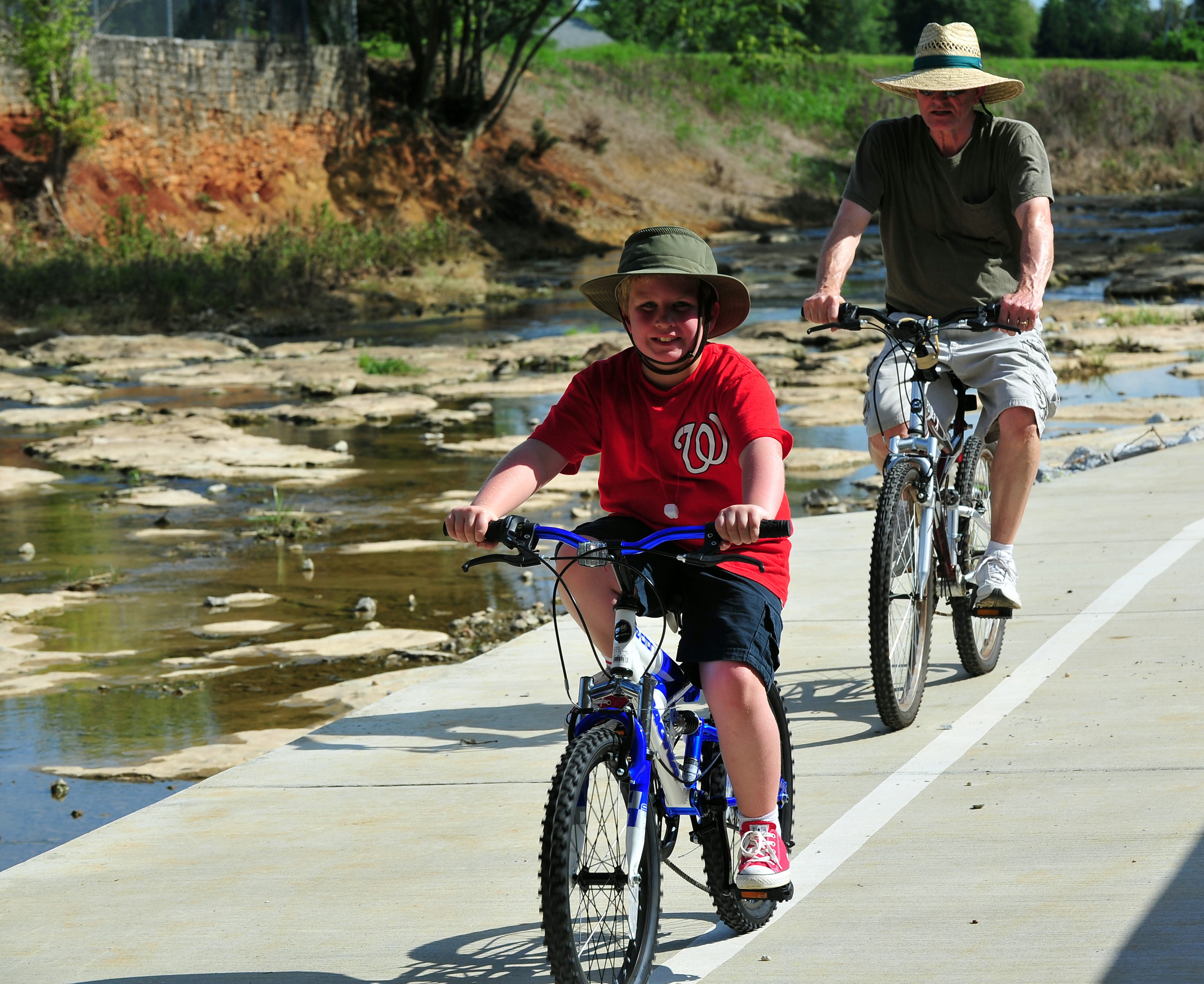 man and a boy ride on bikes on a greenway